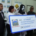 ganhador-de-loteria-recebe-premio-com-mascara-do-panico-para-nao-ser-identificado-na-jamaica-|-g1